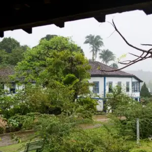 Fachada do casarão histórico da Fazenda Santa Rita em Muqui, cercado por natureza e jardins.