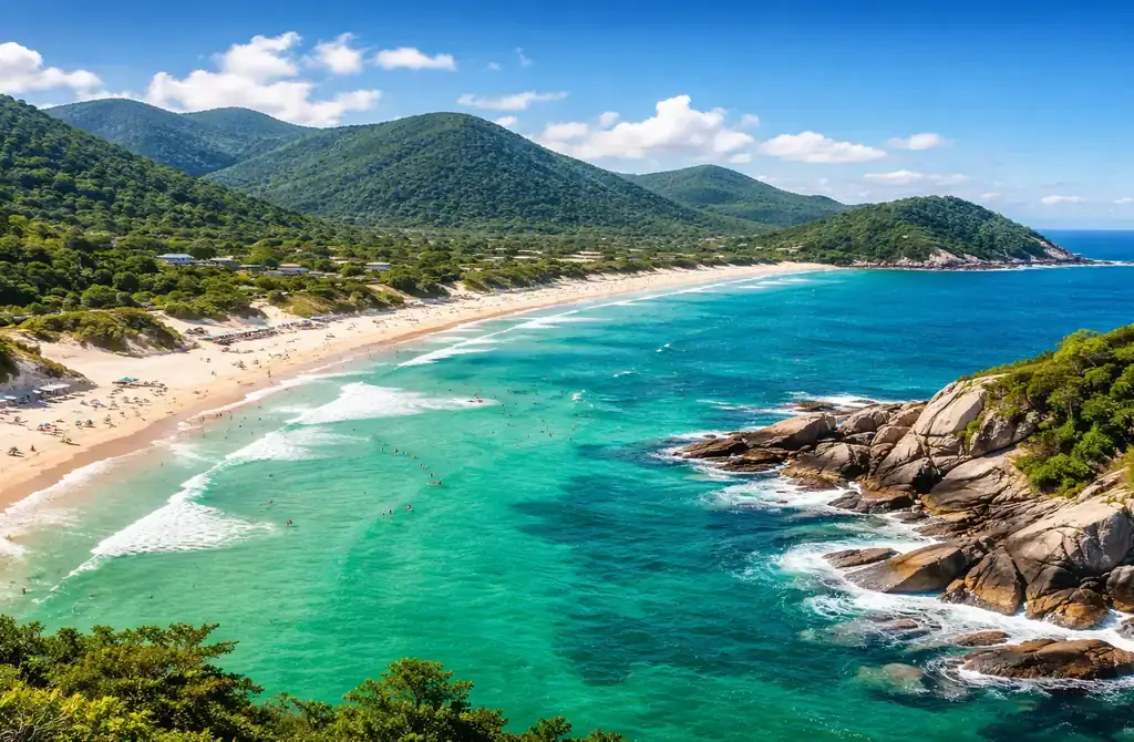 Paisagem aérea de uma praia paradisíaca no Sul do Brasil, com mar verde-esmeralda, areia branca e vegetação nativa, representando o litoral de Santa Catarina.
