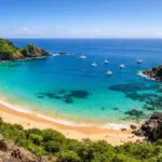 Vista do mirante da Baía do Sancho em Fernando de Noronha, mostrando o mar turquesa e as falésias verdes.