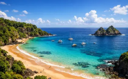 Praias Mais Bonitas do Nordeste em 2026 6 Vista panorâmica da Baía do Sancho em Fernando de Noronha, com mar azul-turquesa e falésias verdes.