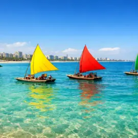 Praia de Pajuçara em Maceió com suas tradicionais jangadas de velas coloridas flutuando sobre águas azul-turquesa.