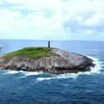 Vista aérea da Ilha Escalvada com seu farol vermelho, principal ponto de mergulho em Guarapari, Espírito Santo.