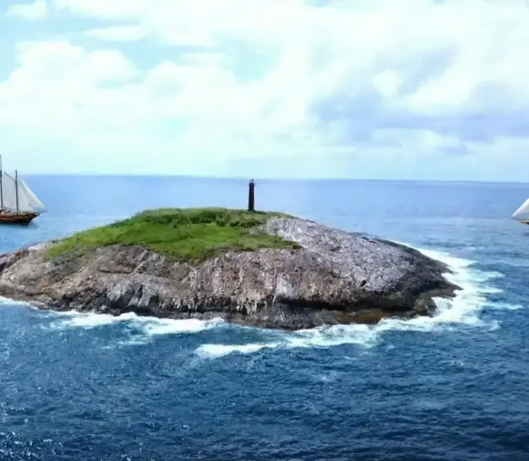 Vista aérea da Ilha Escalvada com seu farol vermelho, principal ponto de mergulho em Guarapari, Espírito Santo.