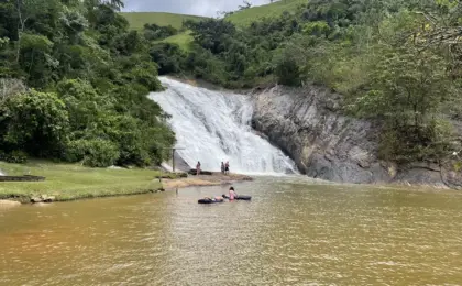 Vista panorâmica da Cachoeira Rio do Meio em Santa Leopoldina, mostrando a ampla queda d'água rochosa e a área de banho com banhistas aproveitando a piscina natural