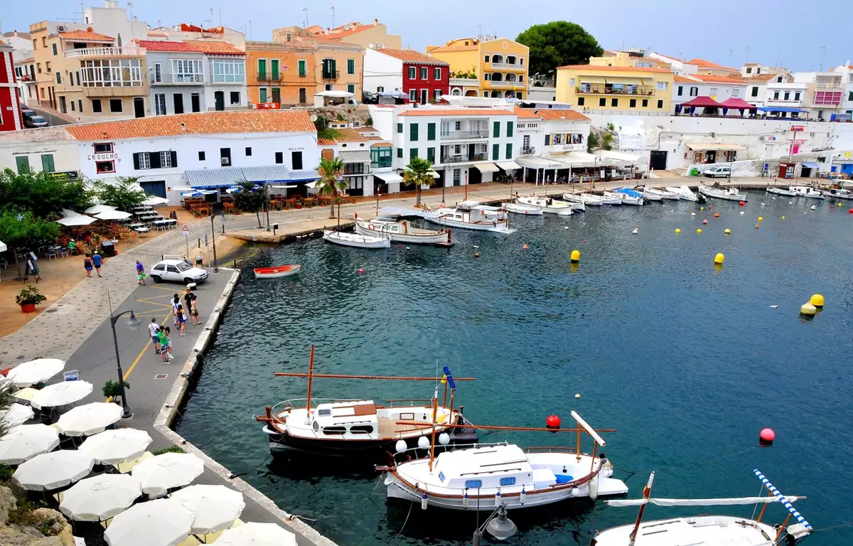 Menorca na Espanha com cala de água azul turquesa falésias e barcos no Mediterrâneo