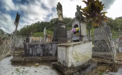 Túmulo de Maria Gilda: O mistério da água em Santa Leopoldina (ES) 10 Foto do túmulo de Maria Gilda no cemitério de Santa Leopoldina, com água visível na superfície da sepultura de concreto.