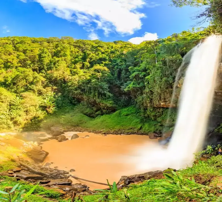 Vista frontal da Cachoeira de Matilde (Engenheiro Reeve) caindo sobre degraus de pedra cercada por mata em Alfredo Chaves.