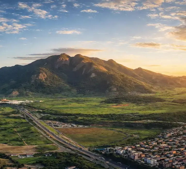 Vista imponente do Mestre Álvaro na Serra, ES, com vegetação de Mata Atlântica e a cidade ao fundo.