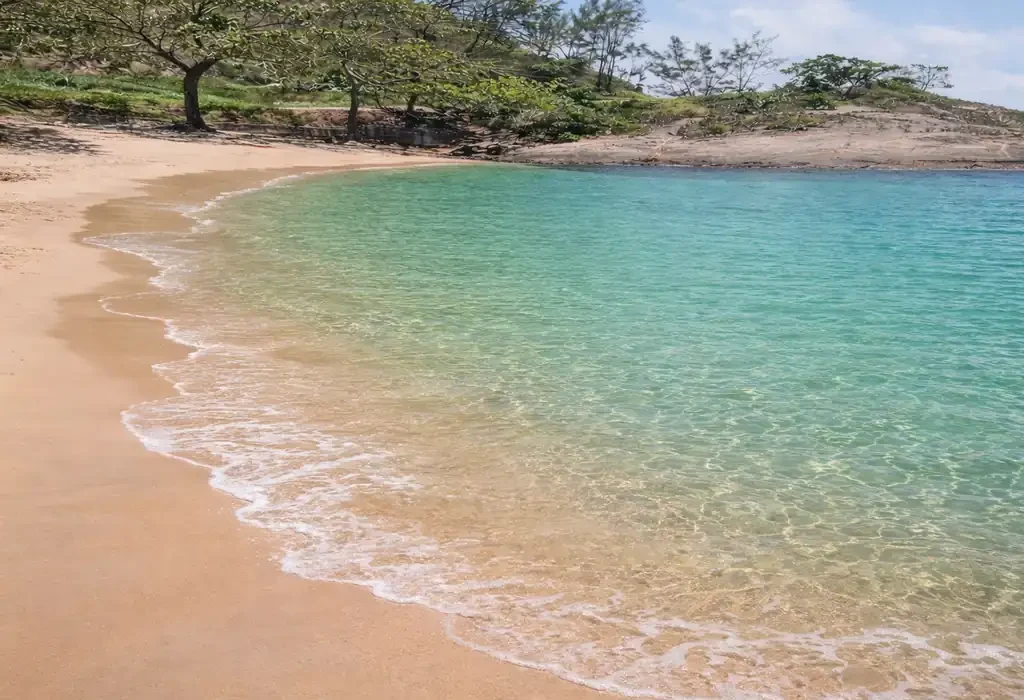 Paisagem da Praia Secreta em Vila Velha com águas cristalinas azul-turquesa e areia dourada aos pés do Morro do Moreno.