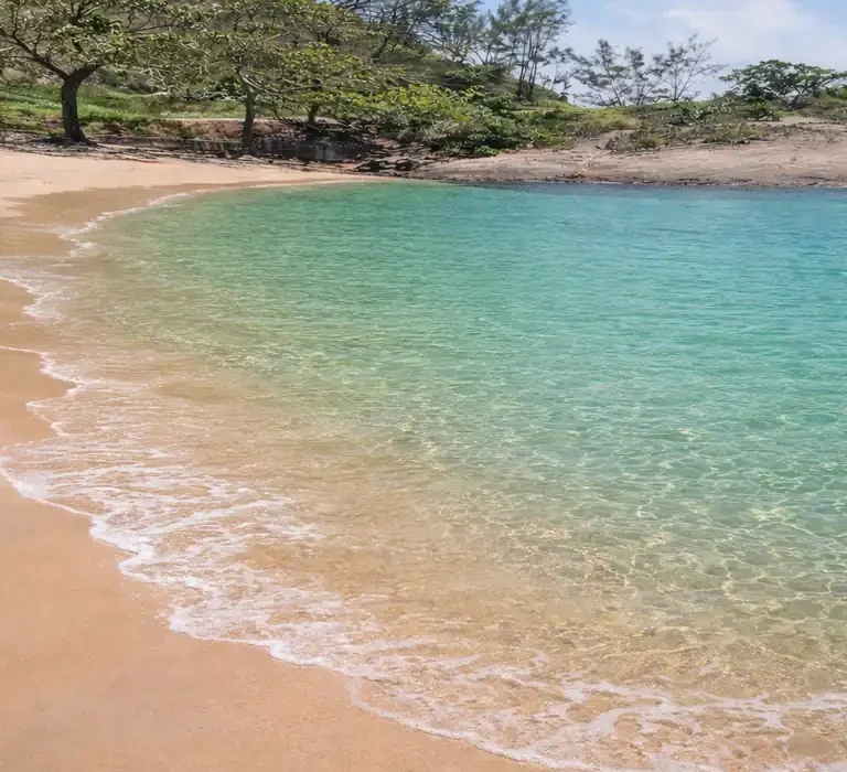 Paisagem da Praia Secreta em Vila Velha com águas cristalinas azul-turquesa e areia dourada aos pés do Morro do Moreno.