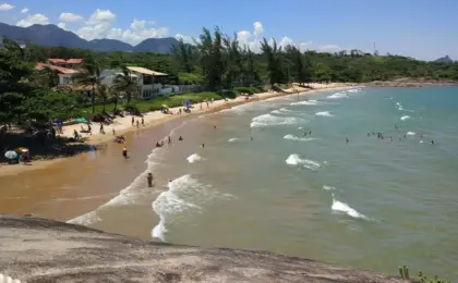 Praia dos Adventistas: O Refúgio Secreto e Tranquilo de Guarapari 15 Vista da Praia dos Adventistas em Guarapari com castanheiras fazendo sombra natural na areia e mar calmo.