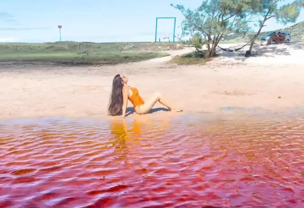 Turista boiando de costas sem esforço na água de tom rosado da Lagoa Vermelha, em Arraial do Cabo.