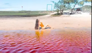 Turista boiando de costas sem esforço na água de tom rosado da Lagoa Vermelha, em Arraial do Cabo.