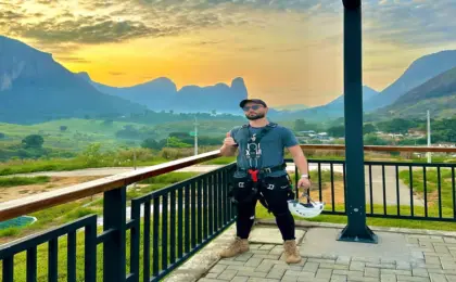 Aventureiro descendo na Tirolesa de Pancas, a maior da América Latina, com os Pontões Capixabas ao fundo.