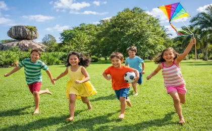 Grupo de crianças felizes correndo com pipa e bola em um parque gramado ensolarado, com uma grande formação rochosa ao fundo lembrando o Parque Pedra da Cebola.