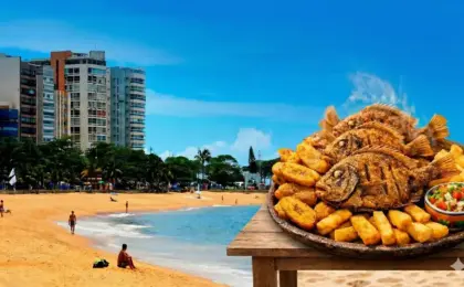Porção generosa de peroá frito crocante com banana da terra e vinagrete, servida em um quiosque de praia ensolarado no Espírito Santo.