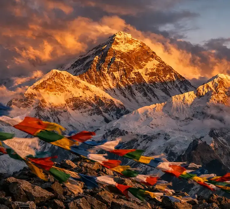 Pico do Monte Everest com nuvens dramáticas e bandeiras de oração, ilustrando o ambiente hostil da Zona da Morte.