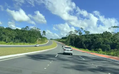 Vista da nova Rodovia ES-115, o Contorno de Jacaraípe, na Serra, Espírito Santo. A imagem mostra pistas duplas asfaltadas, sinalização moderna e fluxo livre de veículos em dia de sol.