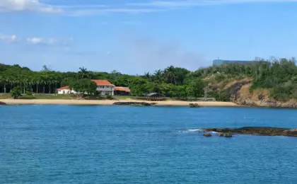 Vista panorâmica da Praia da Casa do Governador em Vila Velha, cercada por mata e pedras, vista a partir do Parque Cultural.