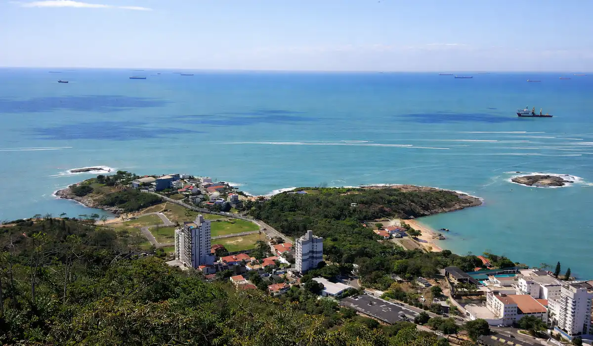 Vista panorâmica da Praia da Casa do Governador em Vila Velha, cercada por mata e pedras, vista a partir do Parque Cultural.