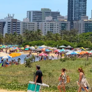 Multidão de banhistas na Praia da Guarderia em Vitória sob céu azul no dia 1º de janeiro de 2026.