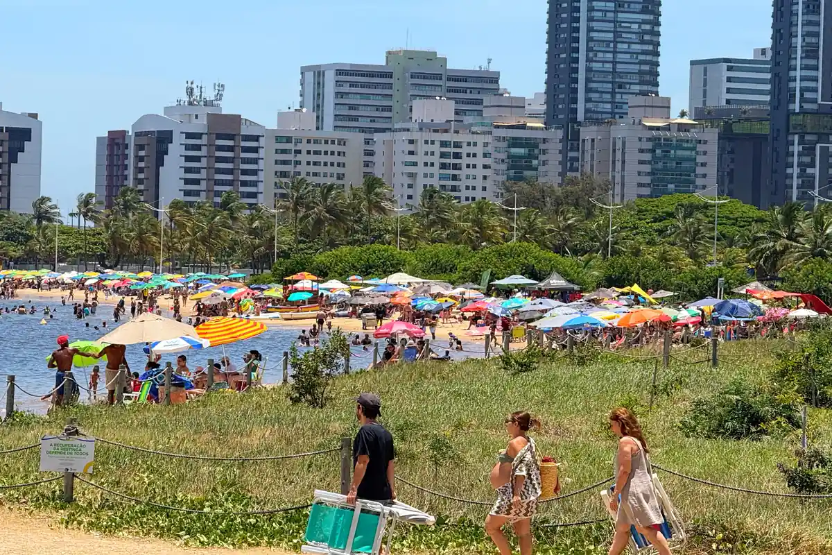 Multidão de banhistas na Praia da Guarderia em Vitória sob céu azul no dia 1º de janeiro de 2026.