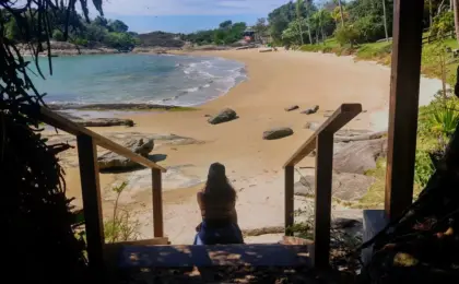Vista da Praia dos Ventos em Guarapari, com mar calmo e transparente e pedras na lateral.