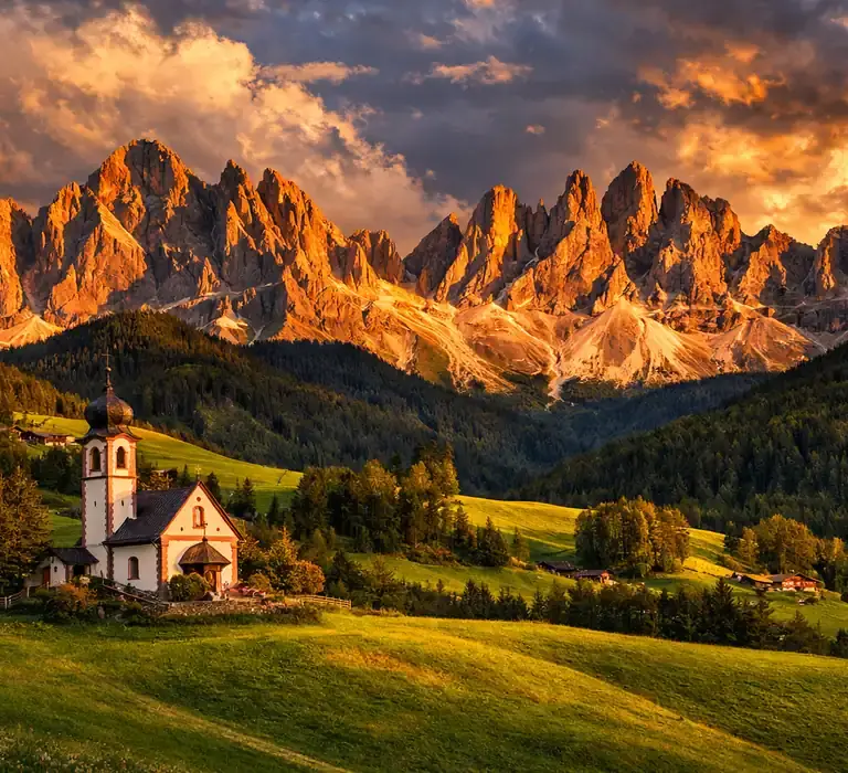 Igreja de Santa Maddalena em Val di Funes com as montanhas Odle ao fundo durante o pôr do sol.